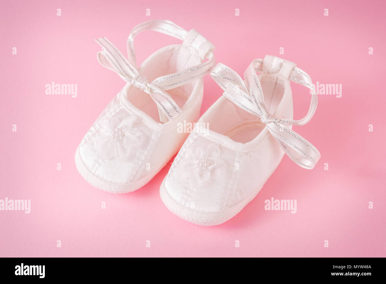 White baby shoes on pink background. A pair of baby shoes. It`s a girl ...
